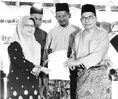  ??  ?? Ahmad Lai (right) presents the government grant to Marini, witnessed by Ahmad Fauzi (second right) and one of SMK Agama Miri’s teachers.