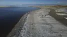  ?? Photograph: Rick Bowmer/AP ?? A couple walks along the receding edge of the Great Salt Lake.