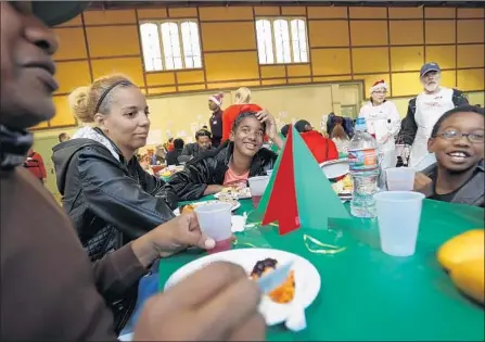  ?? Photograph­s by Luis Sinco Los Angeles Times ?? WAYNE MINGO, left, Emmethia Smith, Kaliyah Smith and Jeremiah Mingo enjoy dinner at Hollywood United Methodist Church.