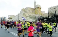  ?? (Ronen Zvulun/Reuters) ?? RUNNERS IN the Jerusalem Marathon are seen outside the Old City last Friday.