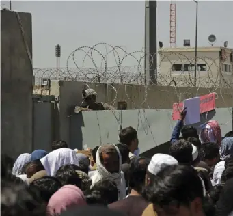  ?? AP ?? HOPING TO LEAVE: U.S. soldiers stand inside the airport as hundreds of people gather near an evacuation control checkpoint outside Hamid Karzai Internatio­nal Airport, in Kabul, Afghanista­n.