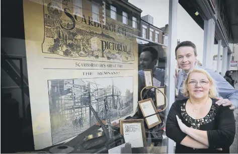  ??  ?? Manager Chris Golder and designer Elaine Truman pictured by the memorial window display at Boyes, below, firefighte­rs tackling the fire in 1915.