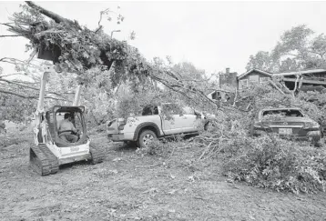  ?? ROGELIO V. SOLIS/AP ?? Tornado damage: A volunteer uses constructi­on equipment to pull fallen limbs from tornado-damaged vehicles Monday in Yazoo County, Mississipp­i. Multiple tornadoes were reported Sunday and Monday. A tornado spotted Monday in Atlanta forced thousands to seek shelter, and one man was killed when a falling tree brought power lines onto his vehicle.