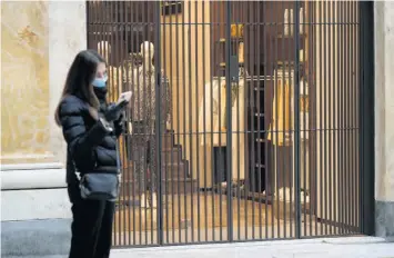  ?? AP ?? Una mujer revisa su teléfono afuera de las tiendas cerradas en el centro comercial Galleria Umberto, en el centro de Nápoles, Italia.