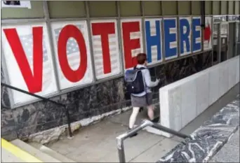  ?? JIM MONE — THE ASSOCIATED PRESS ?? A woman passes a large sign as she arrives to vote Friday in Minneapoli­s. Election Day is more than a month away but the voting was already underway Friday, as Minnesota kicked off its first presidenti­al cycle where all voters across the state can cast...