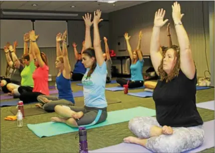  ?? PHOTOS BY MICHILEA PATTERSON — DIGITAL FIRST MEDIA ?? Diamond Credit Union of Pottstown employees raise their hands to the sky as they sit with legs crossed during an after-work yoga class. The class was part of the credit union’s employee wellness program.