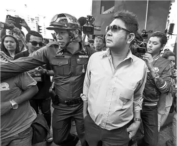  ??  ?? Akkarakit (centre) being detained by a police officer near Victory Monument in Bangkok. — Reuters photo