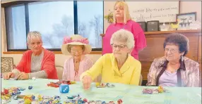  ?? Westside Eagle Observer/SUSAN HOLLAND ?? Melissa Provence (standing), director of the Billy V. Hall Senior Activity Center, looks on as guests play an Easter dice game after the Center’s annual Easter dinner. The day’s activities included a watercolor class, an Easter bonnet contest, the holiday dinner and games. Pictured are LaVonda Augustine (left), Juanita Whiteside, Jeanie Easley and Mary Tipling.