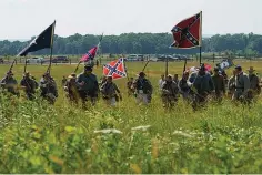  ?? Associated Press ?? ■ Civil War reenactors march with Confederat­e battle flags July 3 during their reenactmen­t of Pickett's Charge at Gettysburg National Military Park. The banner, with its red field and blue X design, is the best known of the flags of the Confederac­y, but the short-lived rebel nation also had other flags.