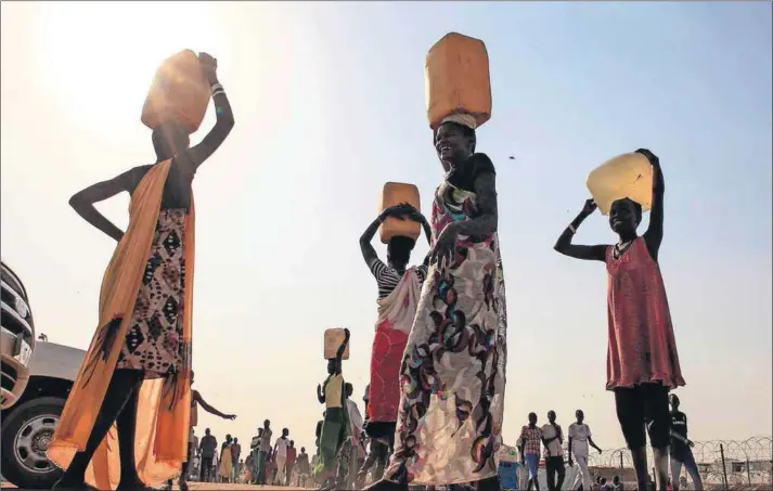  ?? Photos: James Akena/Reuters ?? Dwindling supply: Displaced people collect water at Tomping camp in South Sudan.