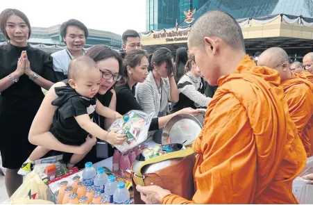  ?? PATIPAT JANTHONG ?? Staff of the Siam Commercial Bank and their families offer alms to monks at the bank’s head office in remembranc­e of the late King Bhumibol Adulyadej who passed away a year ago today. Many companies, large and small, organised merit-making activities...