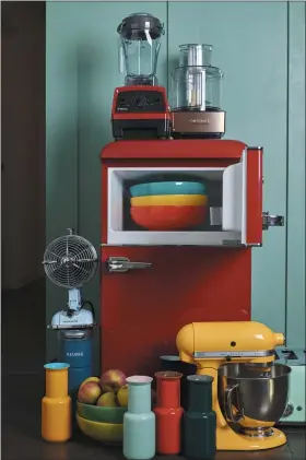  ?? PHOTO PROVIDED BY KATIE WORKMAN ?? This September 2019 photo shows a variety of kitchen items in different colors, including a red fridge, a yellow stand mixer and some brightly colored bowls and vases, in a New York kitchen.