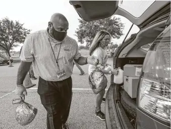  ??  ?? H-E-B employee Victor Nivens and Leanne Schneider with Reliant load food into cars. The number of cars showed how “great the need is” as the pandemic continues to wreak financial havoc.