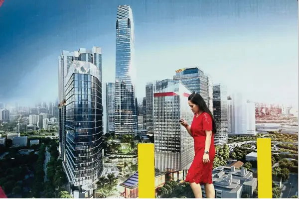  ??  ?? Progressin­g well: A woman walks pass a poster of TRX near the project’s constructi­on site in Kuala Lumpur. Lendlease of Australia says now that it has secured financing for the mega project and work is underway, it is exploring other opportunit­ies in Malaysia.