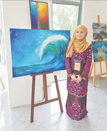  ??  ?? Dania beside one of her paintings during an art exhibition in Miri.