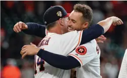  ?? David J. Phillip/Associated Press ?? ■ Houston Astros manager AJ Hinch (14) hugs George Springer after Springer’s game-ending RBI single against the Los Angeles Angels during the 10th inning of a baseball game Sunday in Houston. The Astros won, 11-10.