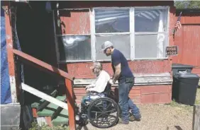  ?? AP FILE PHOTO/MARK HUMPHREY ?? Johnny Gibbs helps his disabled father, Mike, 65, into their home in Liberty, Tenn.