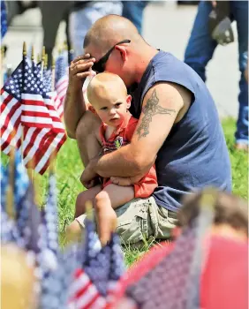  ?? STAFF PHOTO BY DAN HENRY ?? Harrison, Tenn., residents Douglas Deves and his 15-month-old son Hunter visit a makeshift memorial on Friday in front of the Armed Forces Career Center off Lee Highway, where a shooting spree began a day earlier.