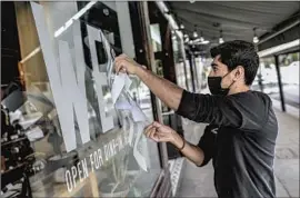  ?? Robert Gauthier Los Angeles Times ?? BONE KETTLE worker Joe Delgado removes a sign at the family- run restaurant in Pasadena after a stint of indoor dining before a new round of COVID- 19 rules.