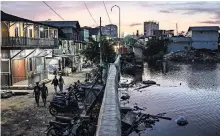  ?? ?? Jakarta, the capital of Indonesia, has grown from less than one million people in 1945 to 30 million today, with 40 percent of the city lying below sea level. Above, a sea wall in one neighborho­od.