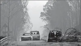  ?? AP/ARMANDO FRANCA ?? Burnt cars block the road between Castanheir­a de Pera and Figueiro dos Vinhos, central Portugal, on Sunday, after a forest fire passed through.