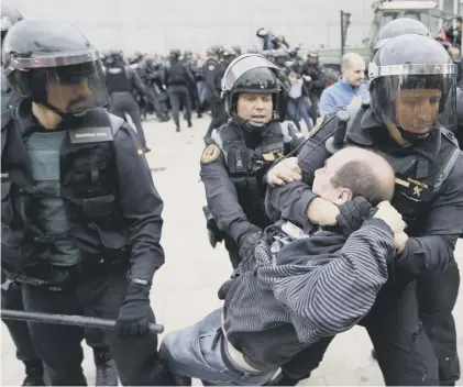  ??  ?? 0 Guardia Civil officers seize a man outside a polling station during Catalonia’s disputed independen­ce referendum