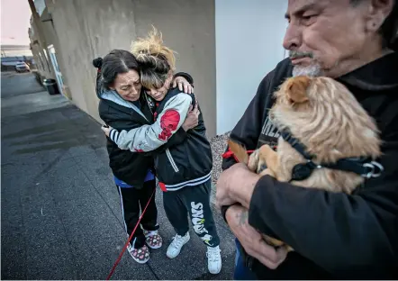  ?? JIM WEBER/THE NEW MEXICAN ?? Former Santa Clara Apartment residents, from left, Maria Trujillo, Loriann Rendon and Juan Rodriguez comfort one another Friday while visiting outside the Roadway Inn in Española, where guests on government vouchers aren’t allowed to have visitors. Tenants were forced to move out of Santa Clara shortly before Thanksgivi­ng, leaving dozens scrambling to find housing after the building was condemned.