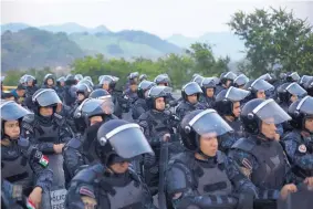  ?? REBECCA BLACKWELL/ASSOCIATED PRESS ?? Mexican federal police in riot gear block the highway outside Arriaga, Mexico, Saturday to keep a caravan of Central American migrants from advancing northward.