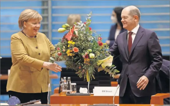  ?? / REUTERS ?? La canciller en funciones, Angela Merkel, recibía un ramo de flores de su previsible sucesor Olaf Scholz, ayer en Berlín.