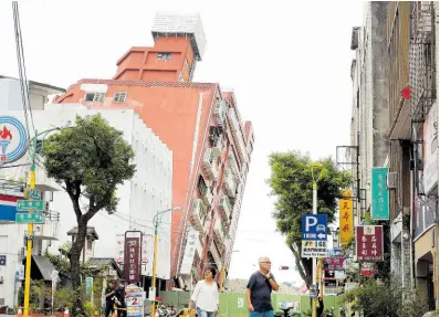  ?? AP ?? People walk past a building, seen partially collapsed, two days after a powerful earthquake struck the city, in Hualien City, eastern Taiwan, Friday, April 5.