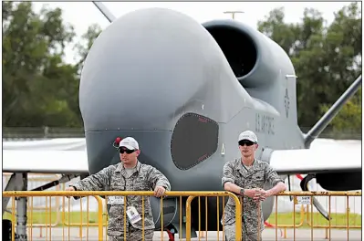  ?? Bloomberg News/SEONG JOON CHO ?? Members of the U.S. Air Force stand in front of a Northrop Grumman Global Hawk surveillan­ce drone this week at the Singapore Airshow. The air show runs through Sunday.