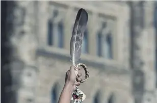  ?? ADRIAN WYLD THE CANADIAN PRESS FILE PHOTO ?? An eagle feather is held up during a rally to raise awareness about missing and murdered Indigenous women and girls. Meggie Cywink, whose sister was slain in 1994, says families are still waiting to hear what government­s have been doing on the MMIWG file.