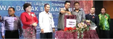  ??  ?? Majang (fourth left) puts his donation into the Gawai Dayak Bazaar 2018 Fund collection box, witnessed by (from second left) Doris, Ganda, Vicky and others.