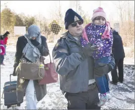  ?? CP PHOTO ?? An RCMP officer escorts a woman and a child claiming to be from Yemen as they cross the U.S.-Canada border in Hemmingfor­d, Que.