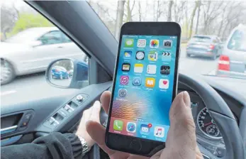  ?? FOTO: DPA ?? Eine Hand am Smartphone, die andere am Lenkrad des Fahrzeugs: Das Unfallrisi­ko steigt durch derart leichtsinn­iges Verhalten um das Sechs- bis Zwölffache.