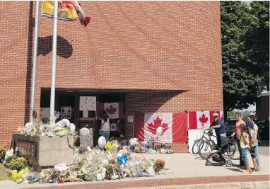  ?? KEITH MINCHIN / THE CANADIAN PRESS ?? Mourners view a memorial for Fredericto­n police constables Sara Burns and Robb Costello last week.