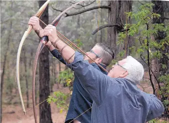  ?? GREG SORBER/JOURNAL ?? Jim Martin, right, and his son, Kyle, draw back their bows outside their Tijeras home. Together, the two have garnered five world flight archery records.