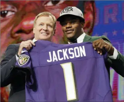  ?? DAVID J. PHILLIP — THE ASSOCIATED PRESS ?? Commission­er Roger Goodell, left, presents Louisville quarterbac­k Lamar Jackson with his Baltimore Ravens jersey to bring the first round of the NFL draft to an end Thursday night. The Ravens acquired the pick in a last-minute trade with the Eagles.