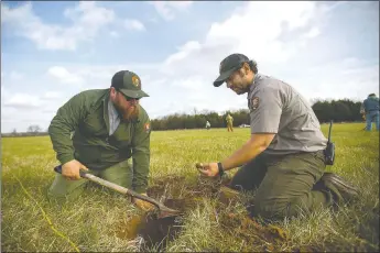  ?? File photo ?? Alex Swift (left), Pea Ridge park interprete­r, and Nolan Moore, park biologist, unearth a piece of case in Ruddick’s Field. Union troops fired their cannons on Confederat­e forces for two hours from a ridge as they pushed back a rebel advance.