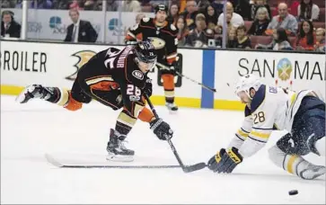  ?? Kyusung Gong Associated Press ?? THE DUCKS’ Brandon Montour shoots past Buffalo’s Zemgus Girgensons during Sunday’s game. The Ducks committed 11 giveaways and were forced to chase the Sabres from behind after an early goal.