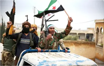  ??  ?? Turkish-backed Syrian fighters raise the opposition flag as they arrive in the border rebel-held town of Qirata after leaving their barracks in the town of Jarabulus on their way to the northern town of Manbij as shown in this file photo. — AFP photo
