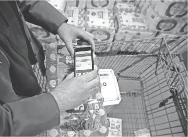  ?? STEPHAN SAVOIA/AP ?? Tony D’Angelo uses the BJ’s Express Scan app on his cellphone to scan a case of bottled water he is purchasing at BJ’s Wholesale Club in Northborou­gh, Mass.