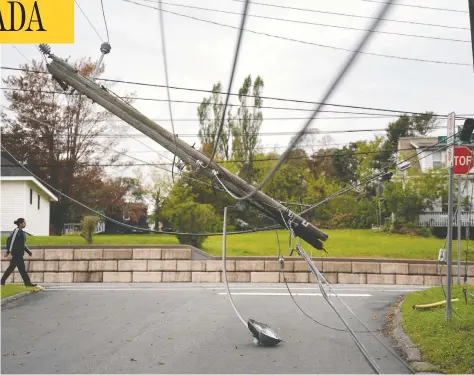  ?? DARREN CALABRESE / THE CANADIAN PRESS ?? A power pole that was ripped out when tropical storm Fiona tore through last weekend dangles over a street in New Glasgow, N.S., on Wednesday.