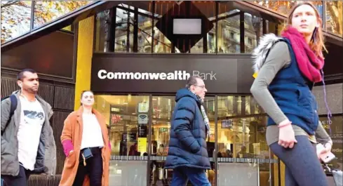  ?? WILLIAM WEST/AFP ?? People walk past a branch of Australia’s Commonweal­th Bank in Melbourne on Monday.