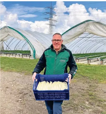  ?? FOTO: SZF ?? Dirk Buchmann vom Schulte-drevenacks-hof mit dem Produkt der Jahreszeit: Spargel. Hinter ihm in den großen Tunneln reifen die Erdbeeren heran.