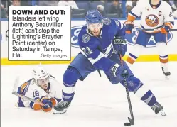  ?? Getty Images ?? DOWN AND OUT: Islanders left wing Anthony Beauvillie­r (left) can’t stop the Lightning’s Brayden Point (center) on Saturday in Tampa, Fla.