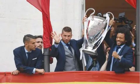  ??  ?? Real Madrid’s Marcelo (right) and Sergio Ramos hold the trophy next to Daniel Ceballos from the balcony of the headquarte­rs of the regional government of Madrid at the Puerta del Sol square in Madrid, as they celebrate their third Champions League...