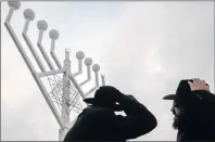  ?? MARKUS SCHREIBER/AP PHOTO ?? Rabbi Yehuda Teichtal, right, and Rabbi Segal Shmoel, left, inspect a giant Hanukkah Menorah at the Pariser Platz in Berlin.