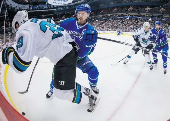  ?? DARRYL DYCK/THE CANADIAN PRESS ?? Captain Henrik Sedin of the Vancouver Canucks checks San Jose Sharks forward Logan Couture into the boards during Thursday night’s NHL game at Rogers Arena. Defenceman Dan Hamhuis of the Canucks keeps Sharks forward Nick Spaling wrapped up behind the play.