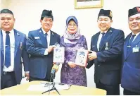  ??  ?? TANDA INGATAN: Hii (dua kiri) menyampaik­an cenderamat­a kepada Fatimah sambil disaksikan Sim (kiri) dan ketua-ketua Kuching Company Boys’ Brigade yang lain.